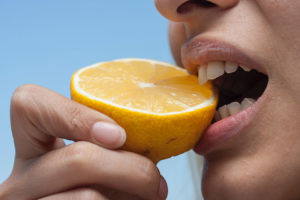 person biting into an orange