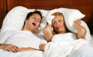Couple in bed while the woman is trying to sleep and the man is snoring