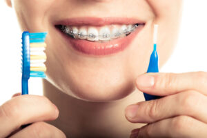 smiling girls with braces and tooth cleaning instruments