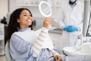 Happy woman looking in a mirror after orthodontic treatment.